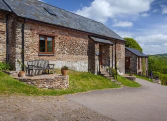 An Exmoor stone barn conversion overlooks a bend in a country lane. 