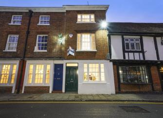 A 3-storey Windsor town house at dusk with windows bathed in light.