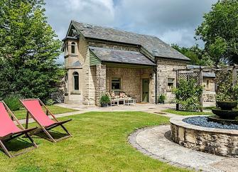 A gsrden path lesds past an ornamental fountain to sa stone. built Somerset holiday cottage