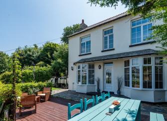 A 2-storey exterior of a Looe holiday let with bay windows and large garden.