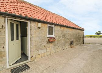 Stone-built bungalow exterior overlooking a paved courtyard in Robin Hoods bay