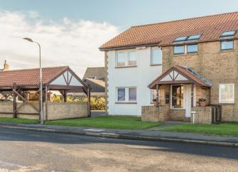 Exterior of a modern semi-detached with an overhead porch and front lawn.