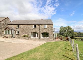 A 2-storey barn conversion overlooks a paved courtyard and open countryside in North Wales.