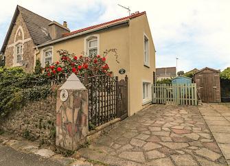 A Torquay holiday cottage sits behind a rose covered stone wall.