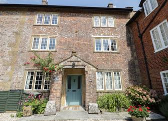 A 3-storey, brick-built, Dorset Mill House overlooks a cobbled courtyard.