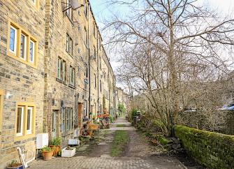 Stone-built exterior of a riverside 4-storey terraced house overlooking a block-paved drive .