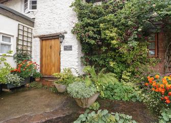 Close up of a farm cottage exterior in The Quantock Hills showing the front door and surrounding shrubbery.