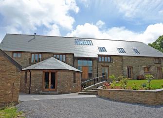 Exterior of a large 2-storey barn conversion surrounded by lawns.