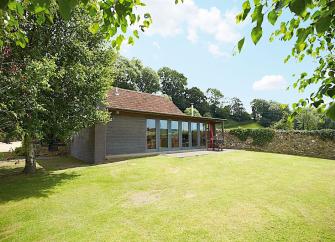 A contemporary wooden holiday lodge in Est Devon overlooking a large walled lawn.