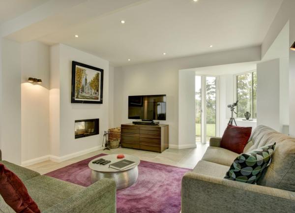 A spacious dual aspect lounge with sofas and lit by down-lighters.