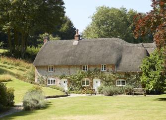 A large thatched cottage overlooks spacious, freshly-mown lawns.