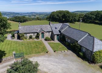 L-shaped exterior of a barn conversion surrounded by open fields.