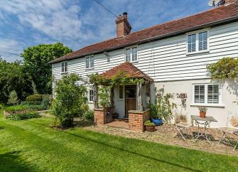 Exterior of a weather-boarded East Sussex Cottage and lawned garden.