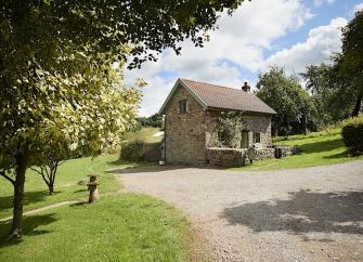 A stone drive leads to a barn conversion surrounded by well-mown lawns.