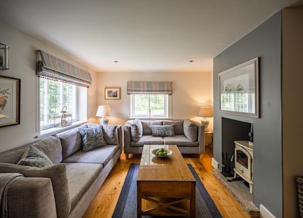 Dual aspect lounge with large wrap-around sofa and wood-burner.