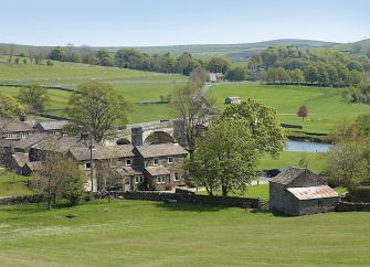 A cluster of houses nestle alongside a stone bridge over a river.