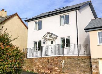 A white-rendered contemporary house fronted by iron-railings.