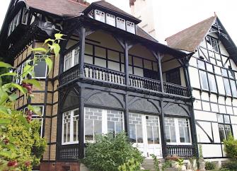 Exterior of a large mock Tudor house with 1st floor balcony.