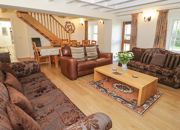 Lounge with three sofas, large pine coffee table, pine floorboards and a dining table with chairs at the rear end.