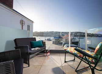 A waterside patio with sun-loungers overlooking an estuary.