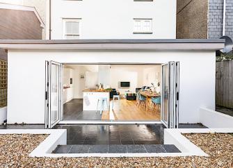 Sliding doors reveal the luxuriously furnished open-plan exterior of a modern holiday cottage.