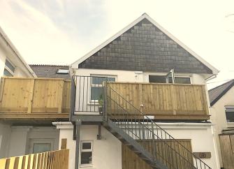 2-storey gable end of a holiday apartment block with stairs and balconies.