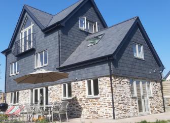 A large, 3-storey detached house built of stone with a 1st floor clad in slates.