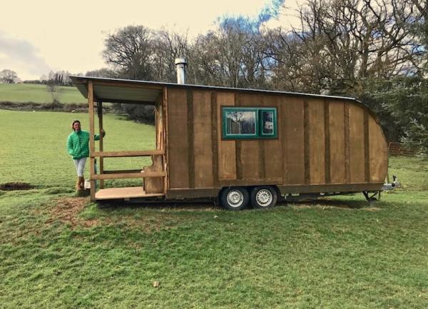 Exterior of an eco-friendly, wooden caravan in a Dorset field.