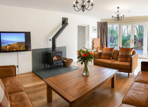 Lounge with 3 sofas, coffee table, TV and woodburner.