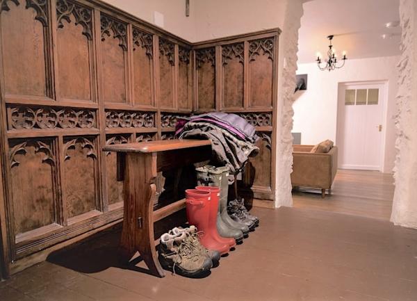 Wood-panelled boot room with drying rack and row of wellies.