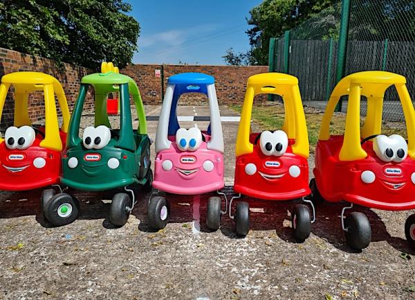 A row of five children's pedal cars waiting for their tiny drivers.