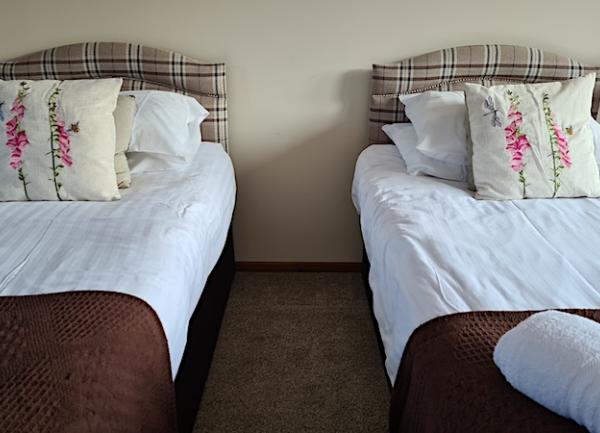 Single beds in a twin bedroom with guest towel sets on the beds.