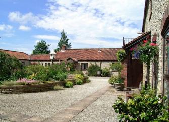 Barn conversions overlook a courtyard with a central flower bed