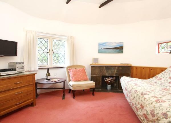 A carpeted lounge with a sofa, fireplace, stereo and a wall-mounted widescreen TV.