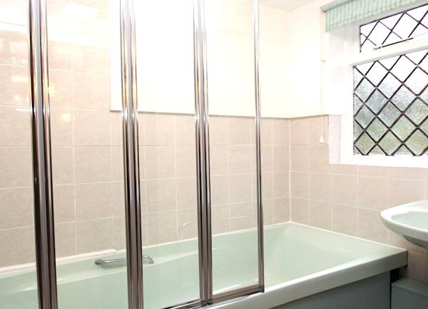 A bathroom with an ovverhead shower and a washbasin.