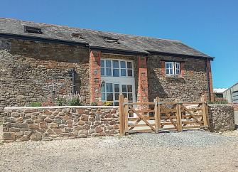 A stone-built North Devon barn conversion overlooks a paved courtyard.