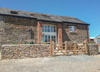 A stone-built North Devon barn conversion overlooks a paved courtyard.