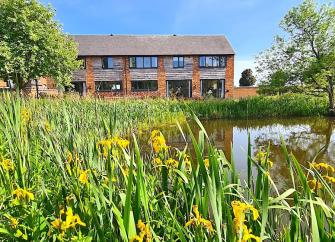 A reed-fringed lake sits in front of a 2-storey Shropshire barn conversion.