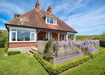 1930s-style detached chalet bungalow with a paved deck surrounded by lawns and the Dorset countryside.