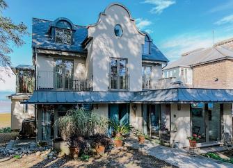 A 4-storey house with balconies and floor-to-ceiling windows within a well-kept, mature garden.