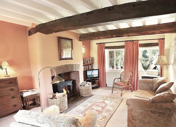 A single-storey cottage overlooks a path lined by flowering lavender and a large lawn. 