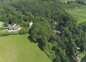 Aerial view of cottages overlooking a river and surrounded by trees.