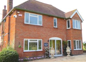 Double-fronted exterior of a rural holiday cottage with a large paved terrace.