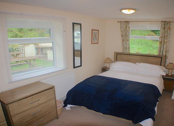 Dual aspect double bedroom with a bed, bedside cabinets with table lights and two chests of drawers.