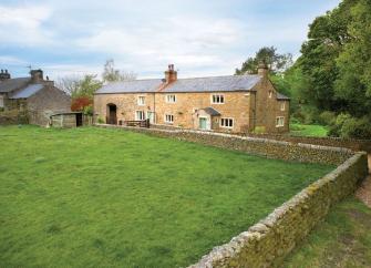 A long country lodge in North Yorkshire overlooking a walled paddock lined by trees