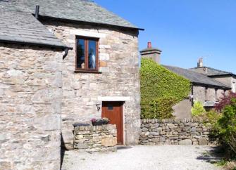 Exterior of a stone built cottage overlooking a courtyard.