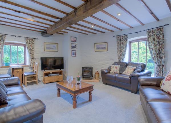 A circular, triple-aspect lounge with TV and 3 matching leather sofas.