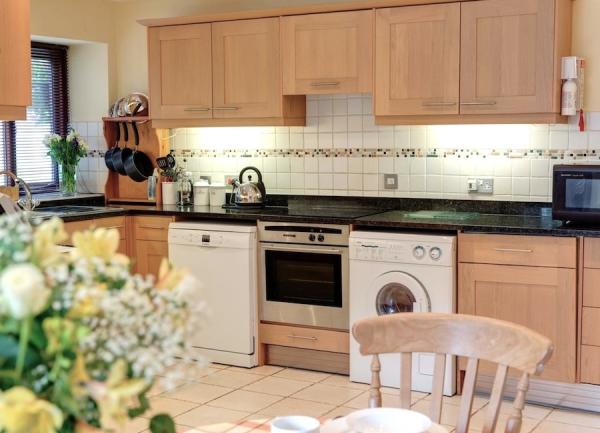 A country-cottage kitchen with fitted units containing a washing machine, dishwasher and oven.