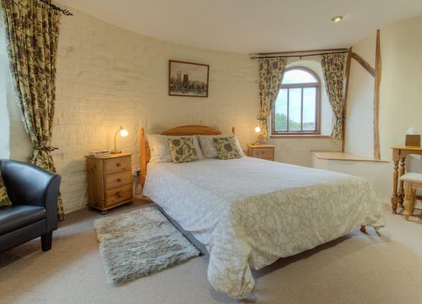 A light, bight double bedroom with an armchair, dressing table