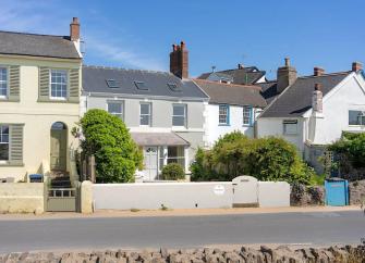 Exterior of a terraced seafront cottage with a walled front garden.
